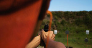 man shooting a gun at a gun range