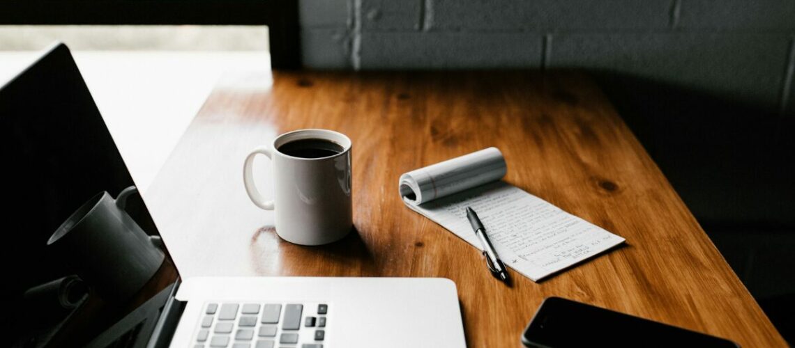 laptop, notepad, phone and coffee mug on a desk