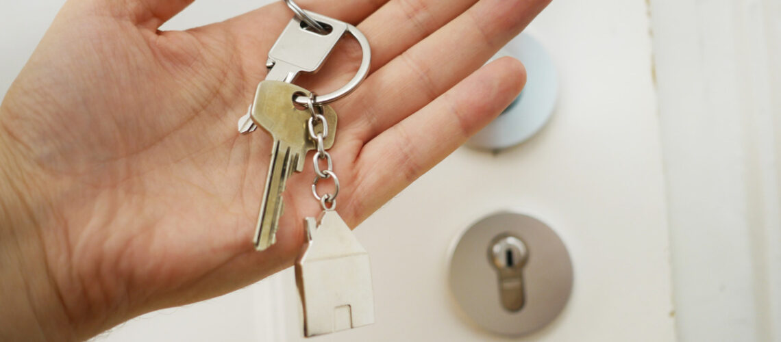 man holding the keys to a house in front of a door
