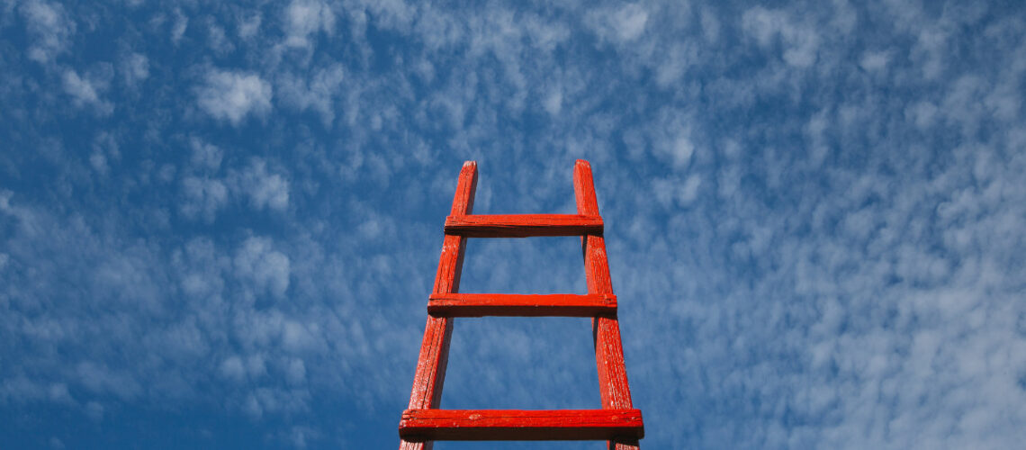 Red ladder against a blue sky with clouds
