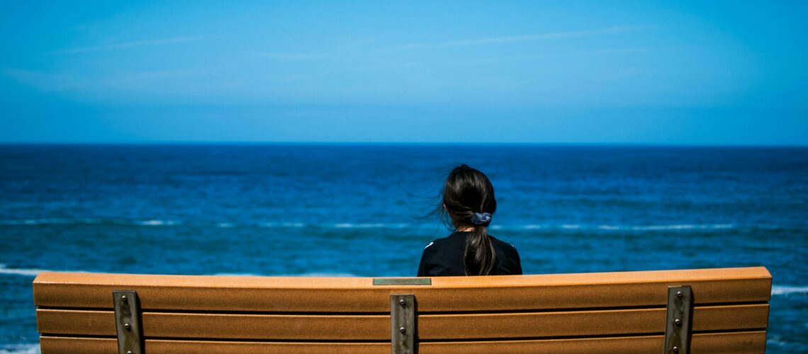 woman on a bench looking out to the ocean